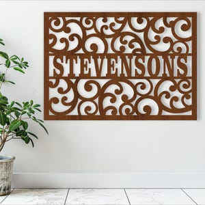 May include: A brown wooden wall decor with a decorative scroll design and the name "STEVENSONS" in the center.