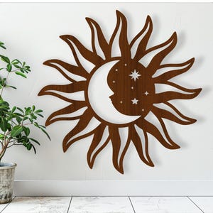 May include: A brown wooden sun and moon wall decor with a crescent moon and stars inside the sun.