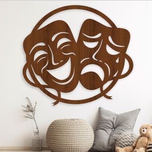 May include: A wooden wall decor featuring two masks, one smiling and one frowning, in a circular frame. The masks are brown and have intricate details.