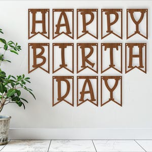 以下が含まれることがあります： 装飾的なフォントで「Happy Birthday」と書かれた茶色の木製バナーです。