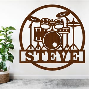 Puede incluir: Un recorte de madera marrón de una batería con el nombre "STEVE" debajo. La batería tiene forma de círculo.