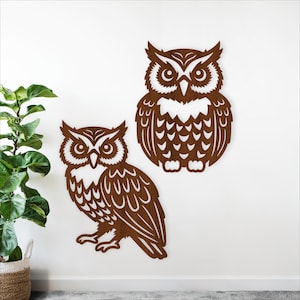 May include: Two brown wooden owl wall art pieces. One owl is perched, the other is a full-body silhouette. Both have detailed feather and eye designs, creating a rustic, nature-inspired aesthetic. The owls are mounted on a white wall.