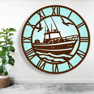 Op de afbeelding: Een ronde wandklok met een nautisch thema. De klok heeft een bruin houten frame met Romeinse cijfers en een lichtblauwe achtergrond. In het midden is een boot afgebeeld, met twee zeemeeuwen die er boven vliegen. De klok heeft een diameter van ongeveer 61 cm.
