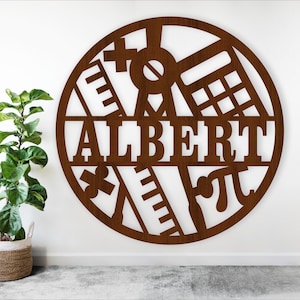 Könnte beinhalten: Ein kreisförmiges Wandkunstwerk aus braunem Metall mit dem Namen "ALBERT" in Großbuchstaben. Das Design integriert mathematische Symbole und Werkzeuge, darunter ein Taschenrechner, ein Lineal und das Pi-Symbol, wodurch ein personalisiertes Dekor entsteht.