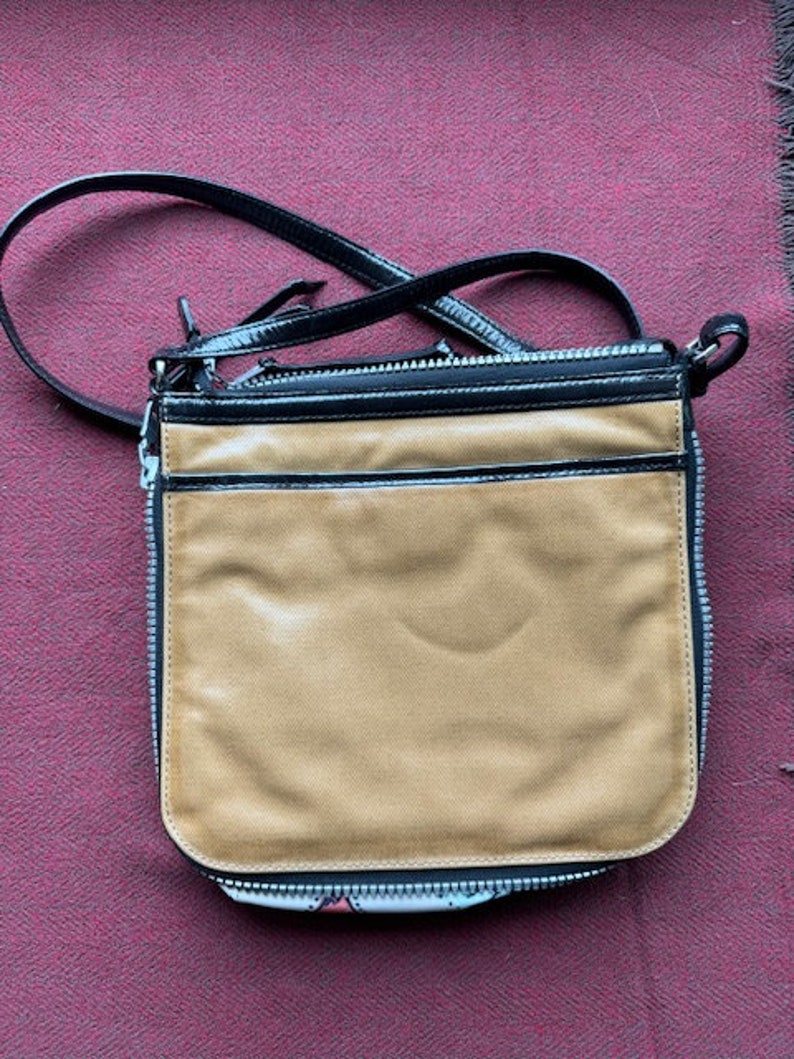 Puede incluir: Un bolso bandolera de cuero marr&oacute;n con una solapa de cuero negro y una cremallera negra. El bolso tiene una correa larga negra.