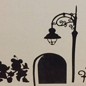 Pode incluir: Silhueta em preto e branco do Mickey Mouse e da Minnie Mouse em pé perto de um poste de luz e um banco. O poste de luz tem um design decorativo e um abajur redondo. O banco tem um design simples com encosto e dois braços.
