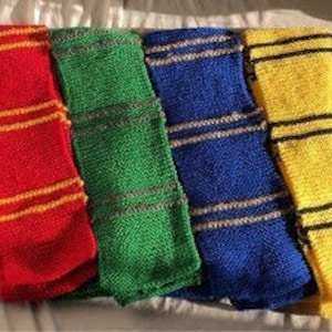 Pode incluir: Quatro cachecóis de malha em cores diferentes: vermelho, verde, azul e amarelo. Cada cachecol tem duas riscas de uma cor contrastante.