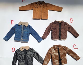 May include: Five miniature jackets in various styles and colors are displayed. The jackets include a brown suede jacket, a blue denim jacket with a faux fur collar, a black leather jacket, and two other brown jackets. The jackets are arranged on a white surface.