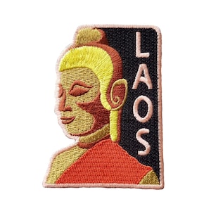 Op de afbeelding: Gestikte patch met een gestileerde afbeelding van een Boeddha in oranje, geel en goudkleuren tegen een zwarte achtergrond. Het woord "LAOS" is in roze gestikt aan de rechterkant van de patch.