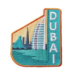 Può includere: Una toppa ricamata con un'immagine colorata del Burj Al Arab hotel a Dubai, con la parola "DUBAI" in lettere bianche sul lato destro.