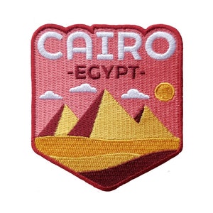 May include: Embroidered patch with a red background and white text that reads "CAIRO - EGYPT-". The patch features a yellow and red illustration of the pyramids in the desert.