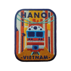 May include: Embroidered patch featuring a train in front of a building with the text "HANOI - VIETNAM" in blue.