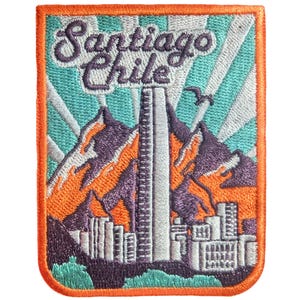 May include: Embroidered patch featuring the text "Santiago Chile" above a cityscape and mountain range. The patch has a teal and white background with orange and purple accents, and a bright orange border.
