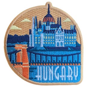 Può includere: Toppa ricamata raffigurante il Parlamento ungherese in blu e arancione. La toppa ha un bordo beige e la scritta "HUNGARY" in lettere blu.