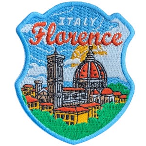 May include: Embroidered patch featuring a shield design with the word "Florence" in orange script, and the word "Italy" above. The patch depicts a cityscape with a cathedral and tower, set against a blue sky and green grass.