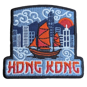 Könnte beinhalten: Ein gestickter Aufnäher mit blauem Hintergrund und dem Text "HONG KONG" in Rot und Weiß. Der Aufnäher zeigt ein rotes und weißes Segelboot vor einer Stadtkulisse mit einer roten untergehenden Sonne.