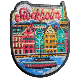 Può includere: Toppa ricamata raffigurante un paesaggio urbano colorato con la scritta "Stockholm" in rosa. Il design include edifici nei toni del rosso, verde acqua e giallo, una barca e una base d'acqua blu. La toppa ha un bordo nero.