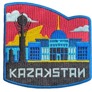 May include: Embroidered patch depicting a Kazakhstan cityscape with a blue building, a tall black structure, and the word "KAZAKHSTAN" in white. The patch has a red and yellow background with blue and white accents.