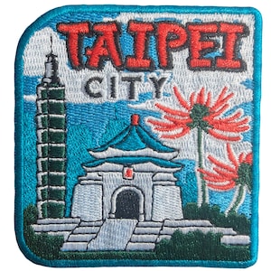 May include: Embroidered patch with the text "TAIPEI CITY" in red and white. The patch shows a tall tower and a traditional building with a blue roof, set against a blue sky with red flowers. The patch has a blue border.