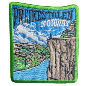 May include: Embroidered patch featuring a scenic view of Preikestolen, Norway. The design includes a blue sky with clouds, a cliff edge, and the text "Preikestolen Norway". The patch has a green border and depicts a landscape with a river.