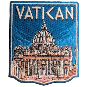 Könnte beinhalten: Gestickter Aufnäher mit dem Vatikan. Der Aufnäher hat einen blauen Hintergrund mit dem Wort "VATIKAN" oben. Das Bild zeigt eine detaillierte Illustration des Petersdoms in Braun-, Beige- und Rosatönen.