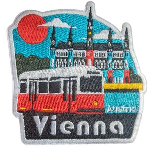 May include: Embroidered patch featuring a red tram and a detailed depiction of a building, set against a blue sky with a red sun. The patch reads "Vienna" and "Austria".