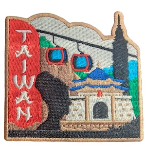 May include: Embroidered patch depicting a Taiwan travel scene. The patch features a red banner with the word "TAIWAN" in white, cable cars, a pagoda, and a tall building. The patch has a brown border.