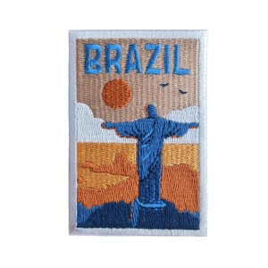 以下が含まれることがあります： 白い縁取りとベージュの背景を持つ刺繍パッチ。パッチには、ブラジルのリオデジャネイロにあるキリスト像の青いシルエットが描かれており、夕日と空に鳥がいます。パッチの上部には青い糸で「BRAZIL」という文字が刺繍されています。