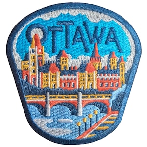 Puede incluir: Parche bordado con la ciudad de Ottawa. El parche tiene un borde azul y representa un colorido paisaje urbano con la palabra "OTTAWA" en azul. El diseño incluye un puente, edificios y un río.