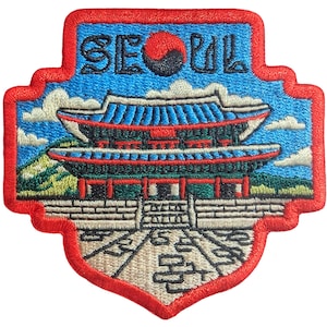 以下が含まれることがあります： 韓国の宮殿の詳細なイラストが刺繍されたパッチ。赤い文字で「SEOUL」と書かれています。パッチは赤い縁取り、青い空の背景、白い雲があります。