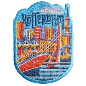 Puede incluir: Parche bordado con la ciudad de Rotterdam. El diseño incluye un barco rojo, un puente y edificios coloridos. La palabra "Rotterdam" está bordada en azul. El parche tiene un borde azul claro.