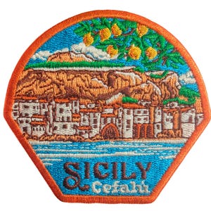 Puede incluir: Parche bordado con una escena de un pueblo costero italiano. El parche tiene un cielo y mar azules, con un pueblo situado contra una montaña marrón. El parche tiene un borde naranja e incluye el texto "SICILY Cefalù".
