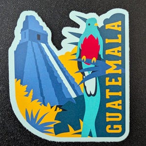 Puede incluir: Una pegatina azul y verde con una imagen estilizada de una pirámide Maya y un pájaro con detalles rojos. El texto "GUATEMALA" está escrito verticalmente en el lado derecho de la pegatina.