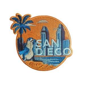 May include: Embroidered patch with a palm tree, a sea lion, and a cityscape with the text "SAN DIEGO" in blue and white lettering on a yellow background.