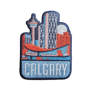 Pode incluir: Etiqueta bordada com uma cidade de Calgary, Alberta, Canadá. A etiqueta é azul, vermelha e branca com a palavra "CALGARY" em letras brancas.