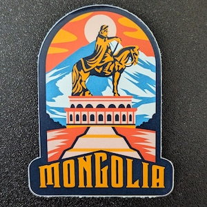 Może przedstawiać: Naklejka z wystylizowaną ilustracją osoby na koniu, z górskim tłem i napisem "MONGOLIA" w kolorze pomarańczowym. Projekt wykorzystuje odcienie niebieskiego, pomarańczowego i żółtego.