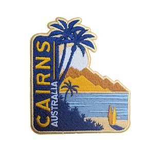 May include: Embroidered patch with a yellow, blue and white design. It features a palm tree, a beach scene and the text "CAIRNS AUSTRALIA".