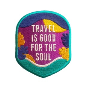 May include: A teal, purple, yellow, and white embroidered patch with the text "TRAVEL IS GOOD FOR THE SOUL".