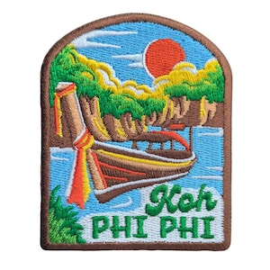 Può includere: Toppa ricamata raffigurante una scena tropicale con una barca a coda lunga, colline verdi e un sole rosso contro un cielo blu. La toppa riporta la scritta "Koh PHI PHI" in verde e bianco.