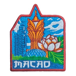 May include: Embroidered patch with the word "MACAD". The patch shows a building, a lotus flower, and a blue sky with clouds. The patch has a red border. The design is in shades of blue, orange, white, and green.