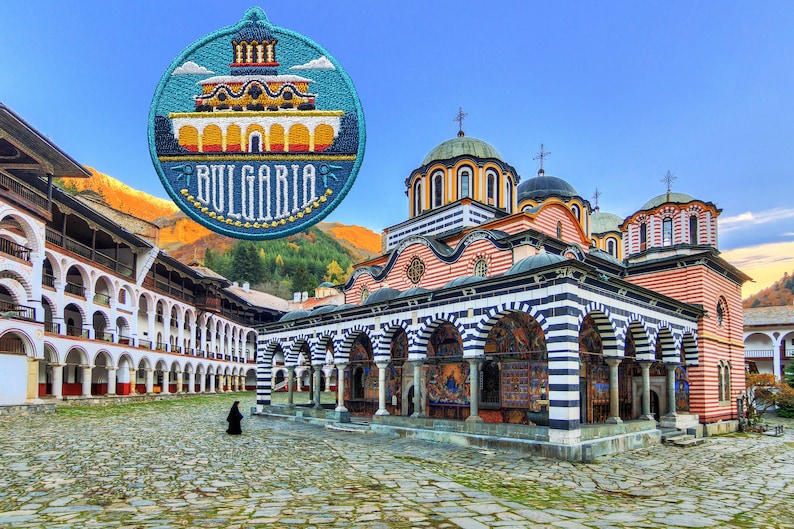 Peut inclure: Un b&acirc;timent color&eacute; &agrave; d&ocirc;mes et &agrave; rayures, avec un portique &agrave; rayures noires et blanches. Le b&acirc;timent est entour&eacute; d'une cour avec un sol en pav&eacute;s. Un petit patch bleu et jaune avec le mot "BULGARIA" se trouve dans le coin sup&eacute;rieur gauche de l'image.