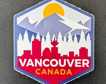 Puede incluir: Una pegatina hexagonal con un diseño de Vancouver, Canadá. El diseño incluye un horizonte rojo, montañas blancas, un sol amarillo y el texto "VANCOUVER CANADA" en rojo y amarillo.