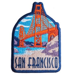 May include: Embroidered patch featuring the Golden Gate Bridge in orange, with blue water and sky, and a sandy beach. The patch has a dark blue border and the words "SAN FRANCISCO" in white.