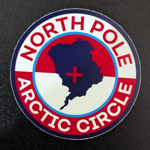 Puede incluir: Adhesivo redondo con la inscripción "NORTH POLE ARCTIC CIRCLE". El diseño incluye un mapa azul, una cruz roja y bandas rojas y blancas. Ideal para viajeros.