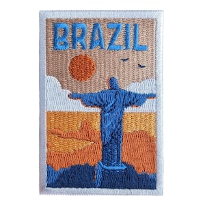 Puede incluir: Parche bordado con la palabra "BRAZIL" en azul. Representa la estatua del Cristo Redentor, un sol naranja y un paisaje. El parche tiene un fondo beige y un borde blanco.
