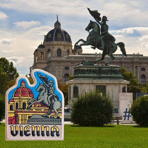 Może przedstawiać: Naszywka haftowana w kolorze białym i beżowym z kolorową ilustracją budynku i powozu ciągniętego przez konie. Tekst "Vienna" jest wyszyty czarnymi, ż&oacute;łtymi i czerwonymi literami na naszywce.