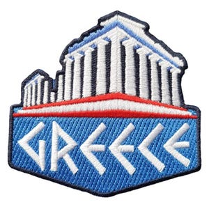 Puede incluir: Parche bordado que representa un templo griego estilizado con columnas blancas y un tejado azul y blanco. El parche tiene un fondo azul con la palabra "GREECE" en letras blancas estilizadas. Una franja roja y blanca está encima de la palabra.