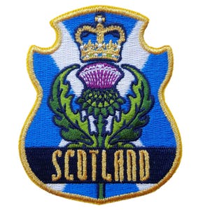 May include: Embroidered patch featuring a shield design with a blue background and a white cross. The patch includes a purple thistle, a gold crown, and the word "SCOTLAND" in gold lettering. The border is gold.