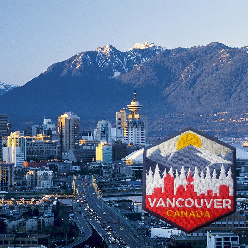 May include: A scenic view of Vancouver, Canada, featuring a cityscape with mountains in the background. A patch with a mountain and cityscape design is in the foreground, with the text "Vancouver Canada".