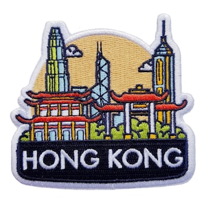 Puede incluir: Parche bordado con la silueta de Hong Kong, con edificios emblemáticos y arquitectura tradicional. El parche tiene un borde blanco y una pancarta negra en la parte inferior con el texto "HONG KONG".